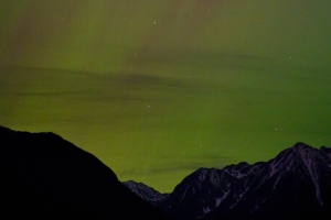 an aurora borealis over the mission mountains, the sky full of stars