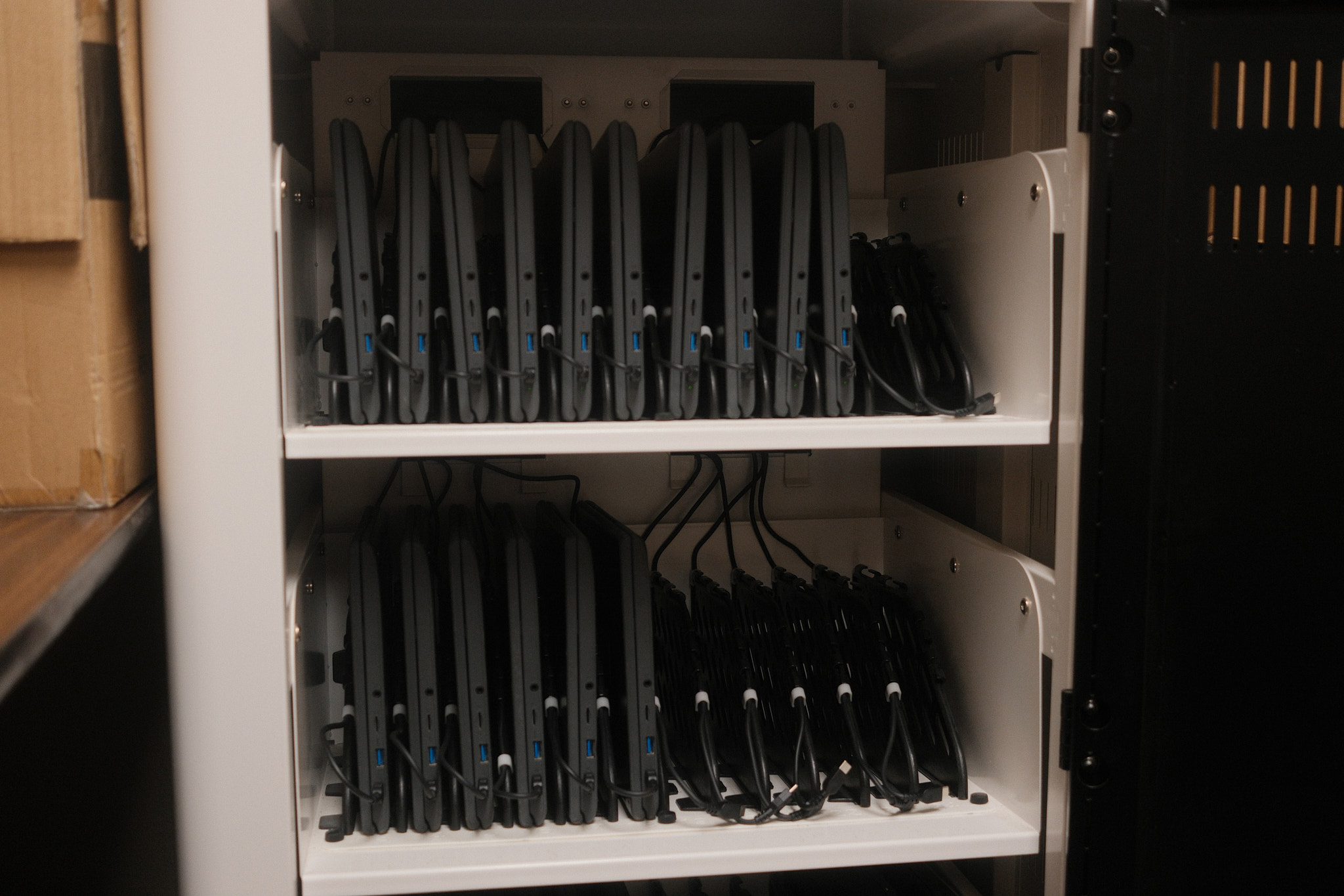 a Chromebook charging cart with 16 recently fixed Chromebooks filed vertically and charging