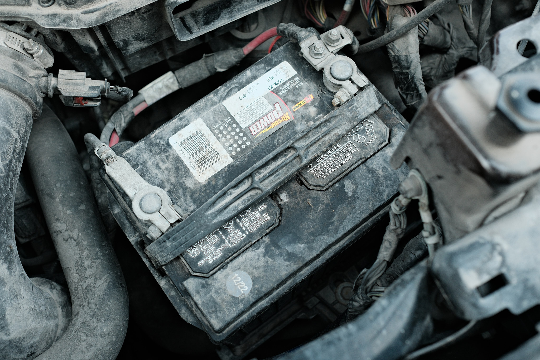 a dirty car battery from a Jeep Patriot connected to the car