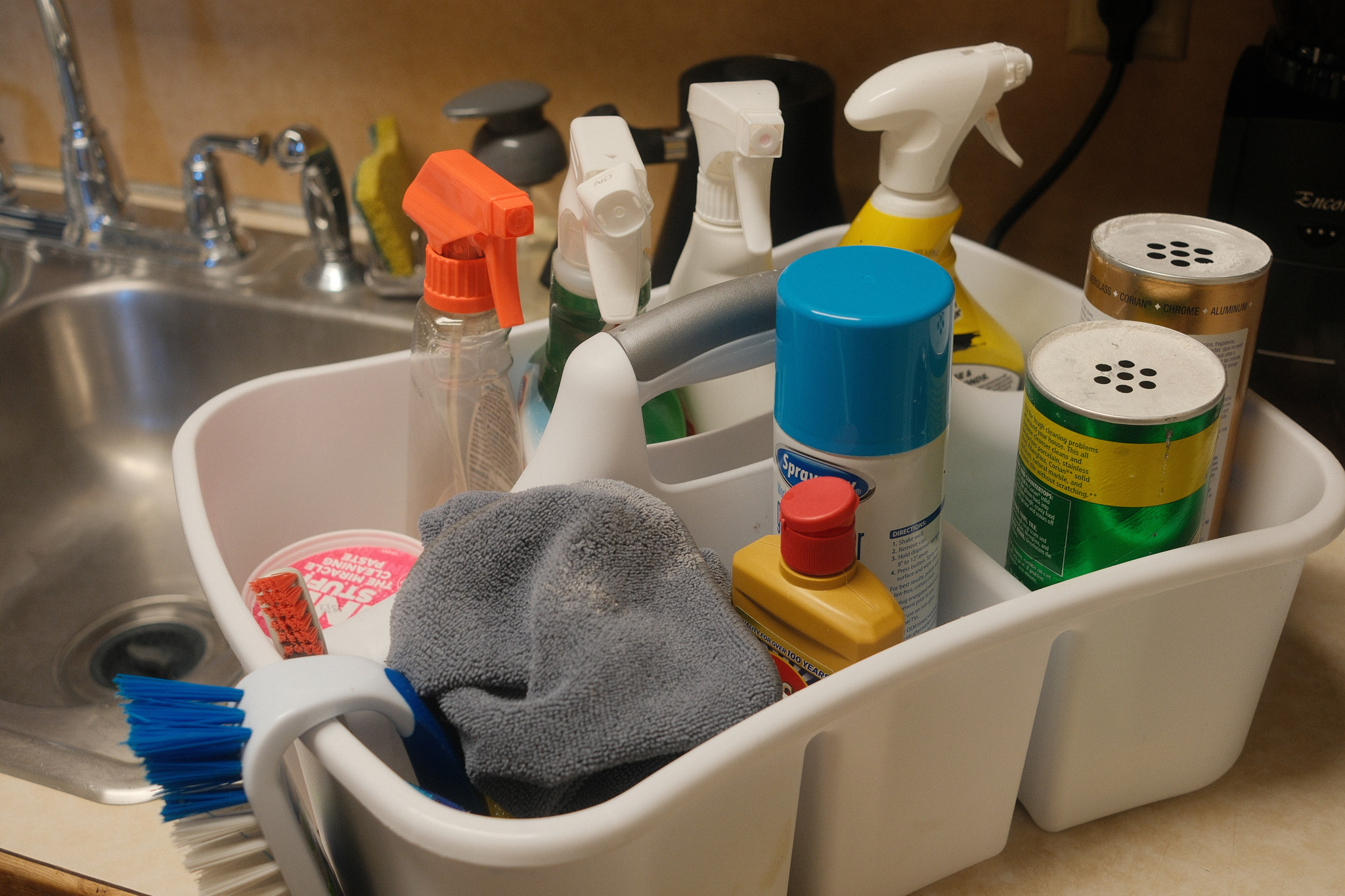 a collection of various cleaning supplies on a kitchen sink