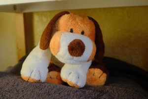 a puppy dog stuffed animal sitting on a stack of bath towels and looking off camera