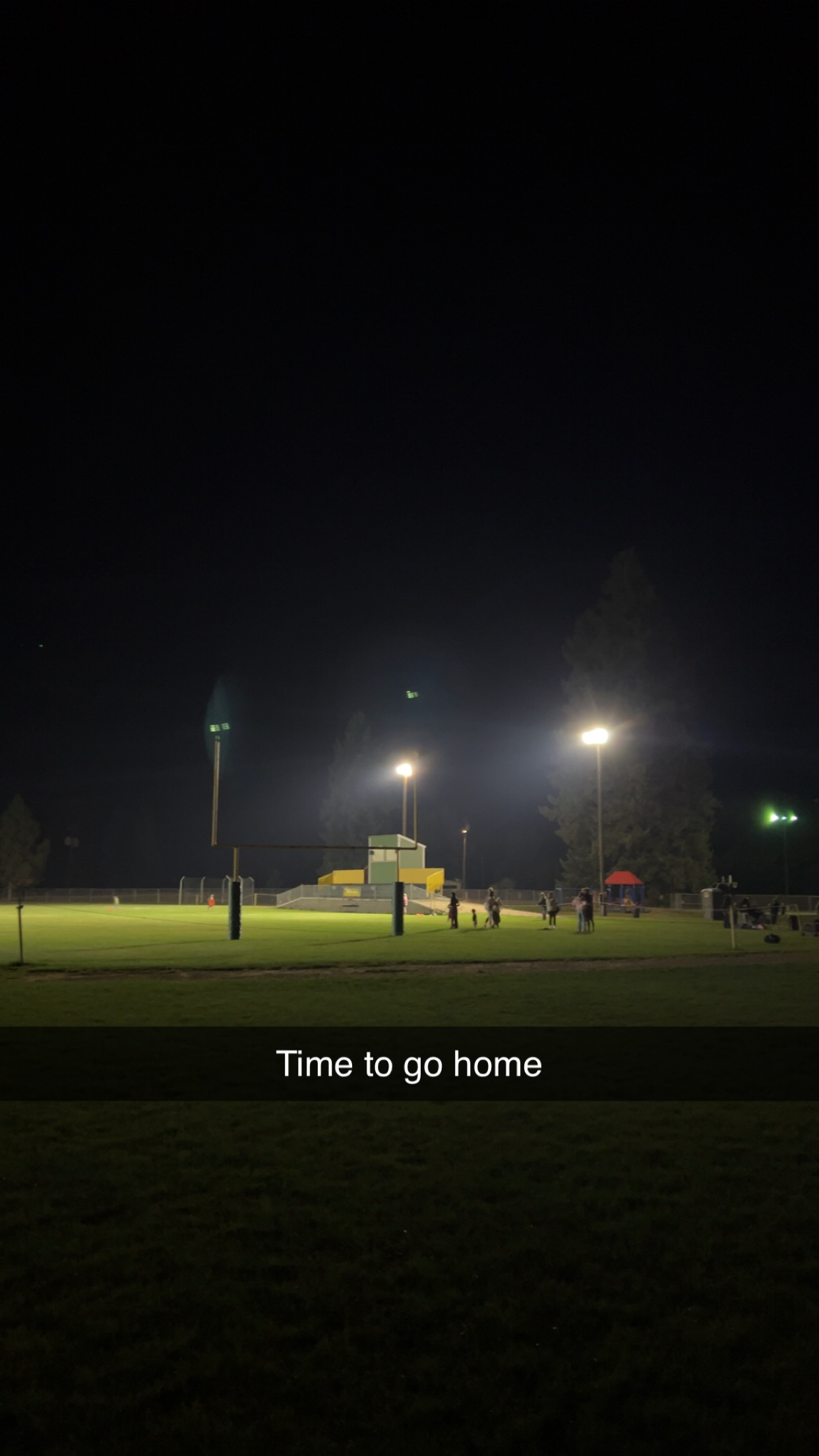 Football field lit up by field lights on a Saturday night with the caption 'Time to go home'