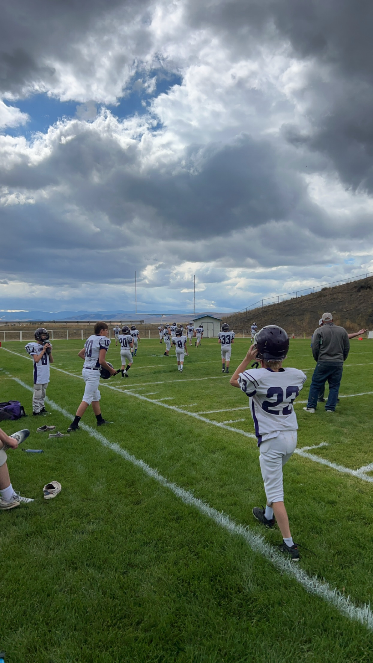 A team of middle school football boys in full uniform and pads getting ready for a game under a cloudy Montana sky