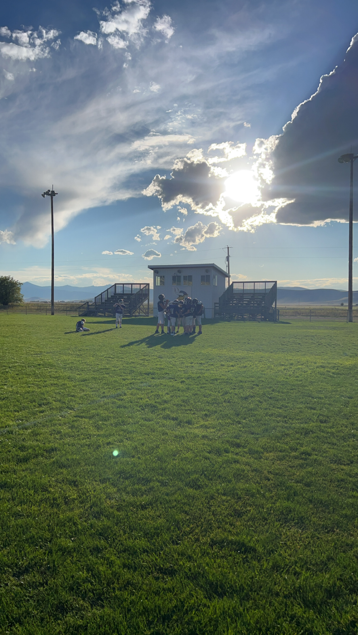 Middle school football boys huddling around together during practice.