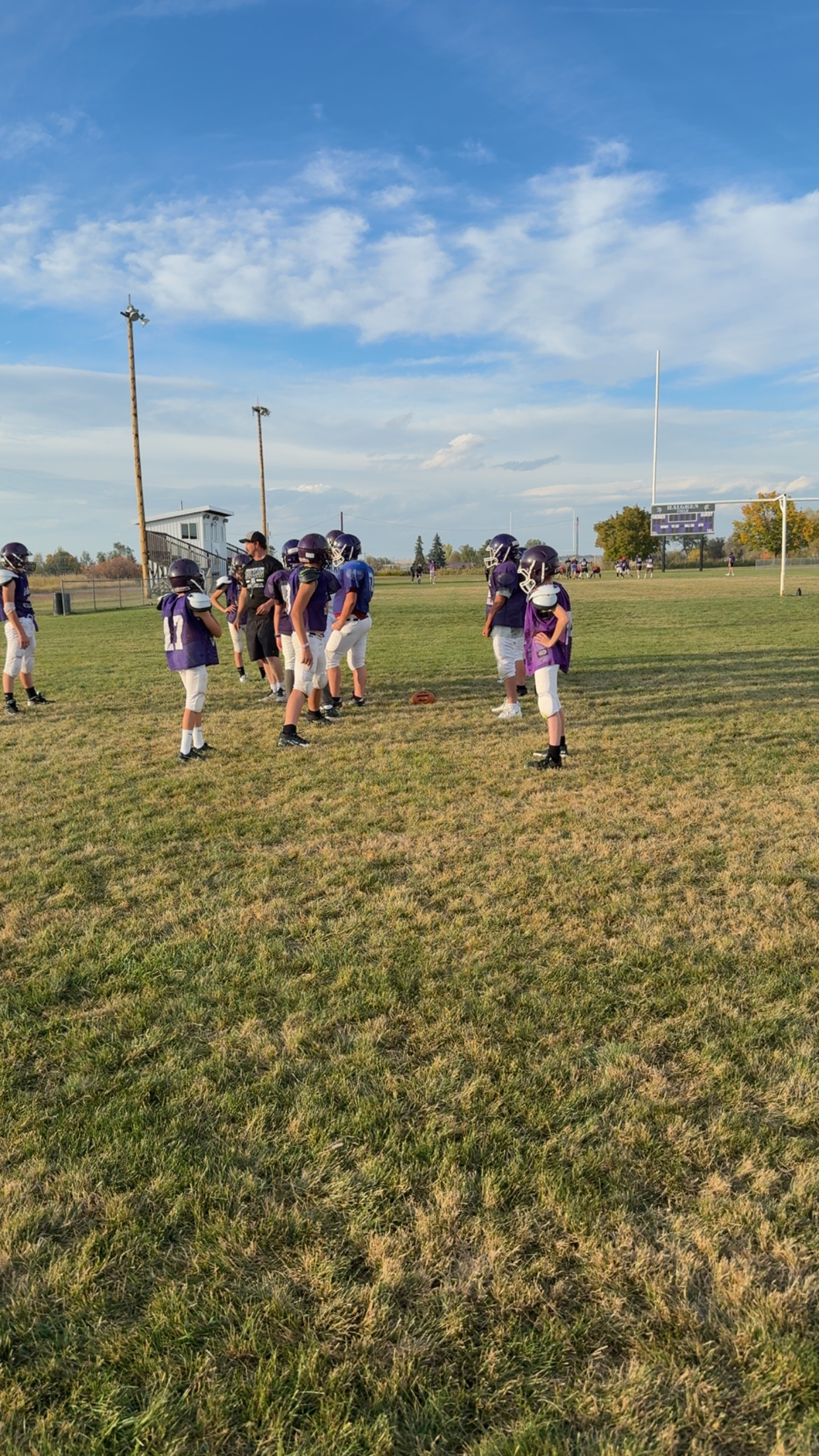 A coach instructing the middle school football boys on a play during practice