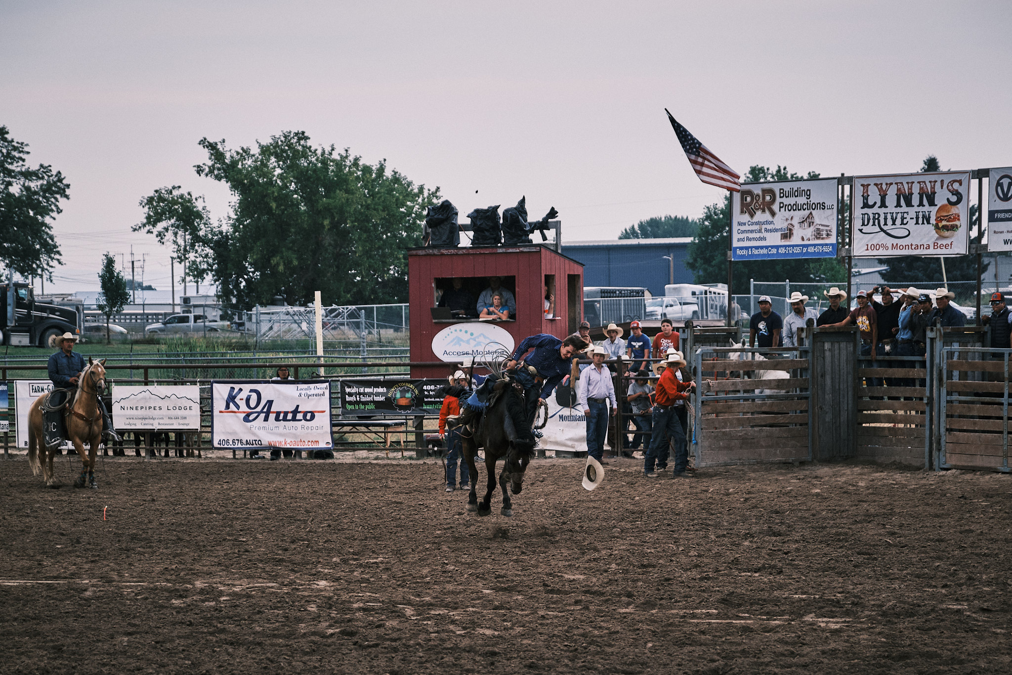 A cowboy about to fall off his horse. He has lost his hat.