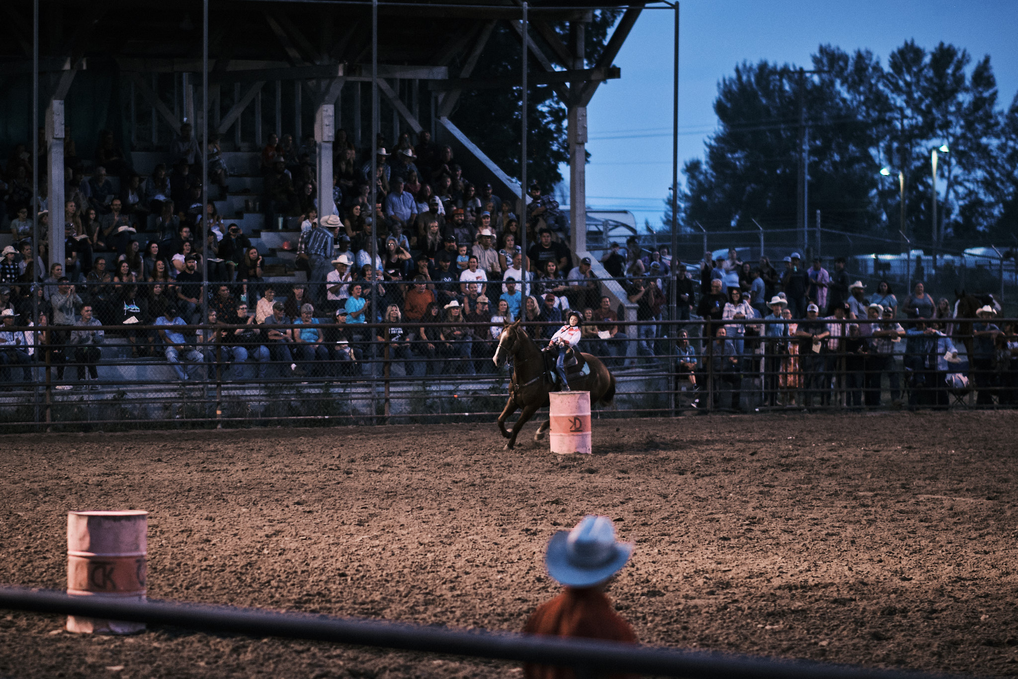 A young cowgirl barrel racing her horse around a barrel